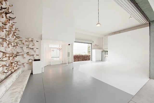 Studio West — bright white open studio with grey epoxy floor, the skull-and-horn wall on the left, and an open roll-up garage door