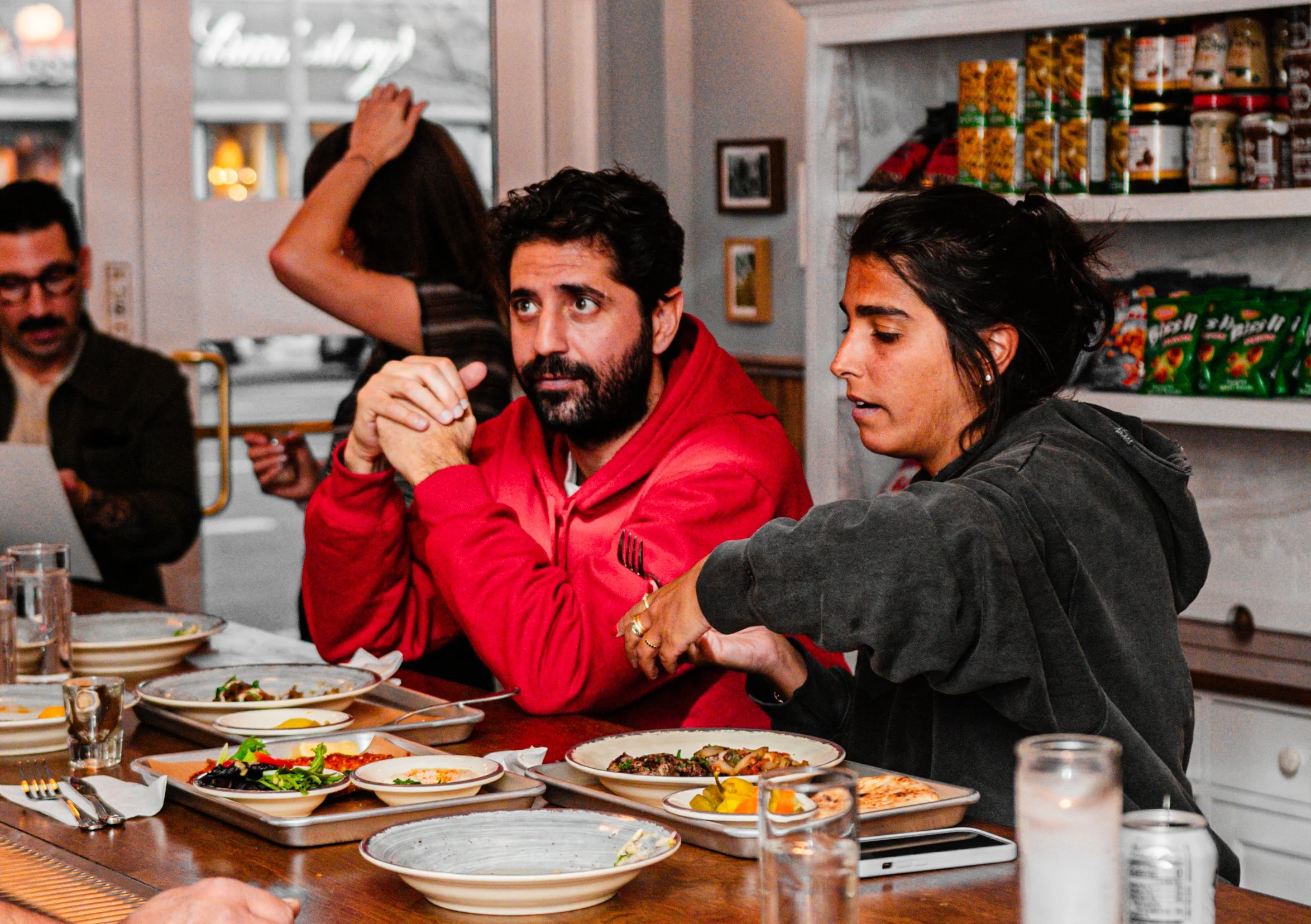 People sitting around a dining table enjoying plates of food and salads in a restaurant setting.
