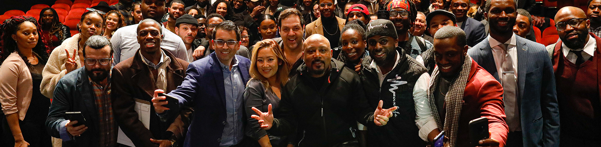 A large group of people posing together at a Fueled by Culture event featuring Daymond John