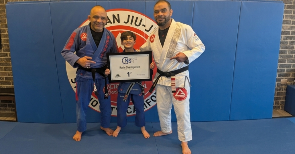 Two instructors and a young student holding a competition award certificate
