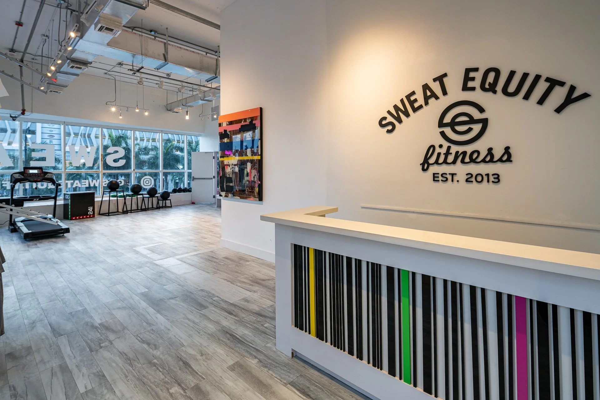 Sweat Equity Fitness reception desk with the Est. 2013 wall sign