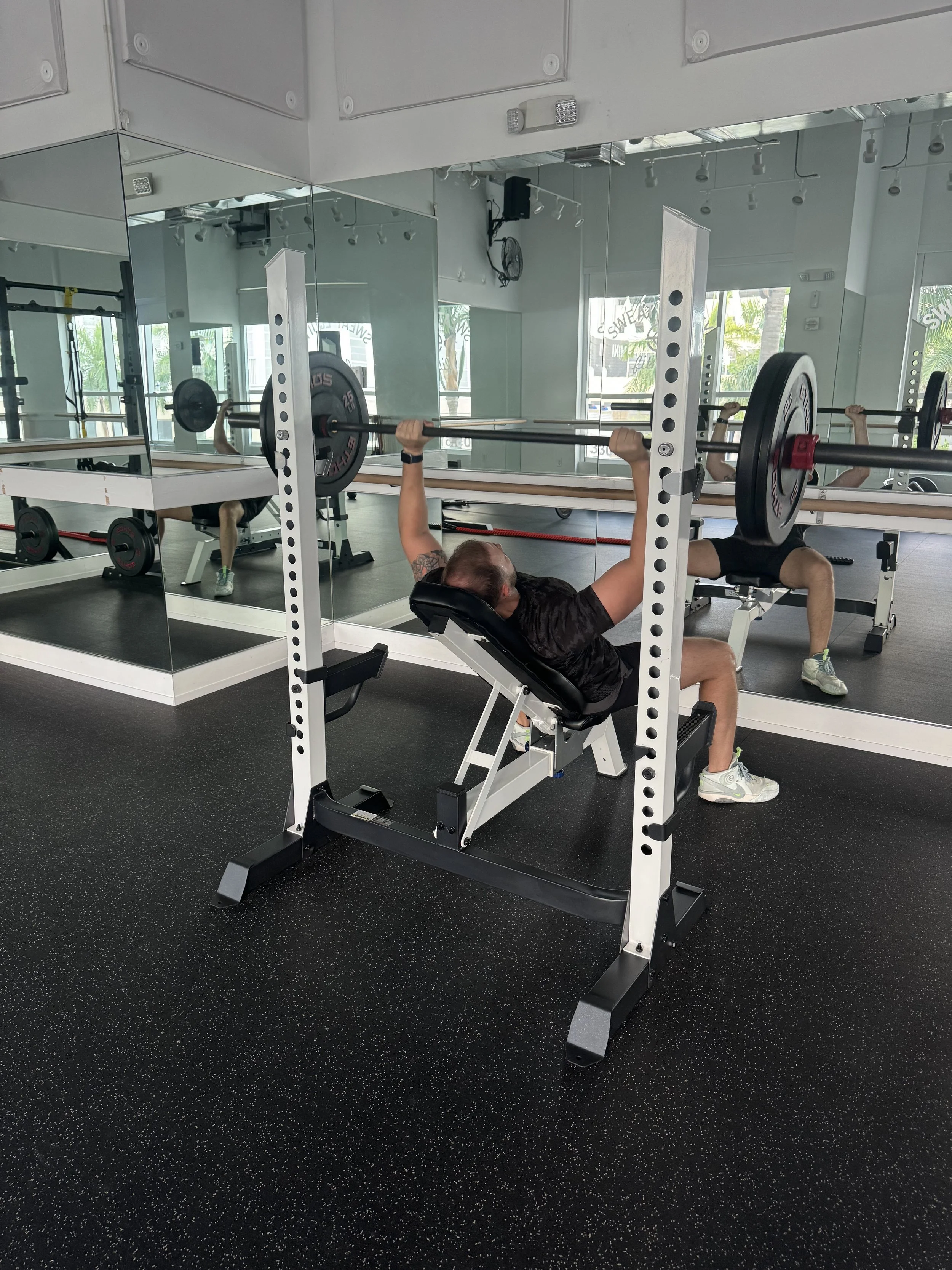 Man performing incline barbell bench press at Sweat Equity Fitness