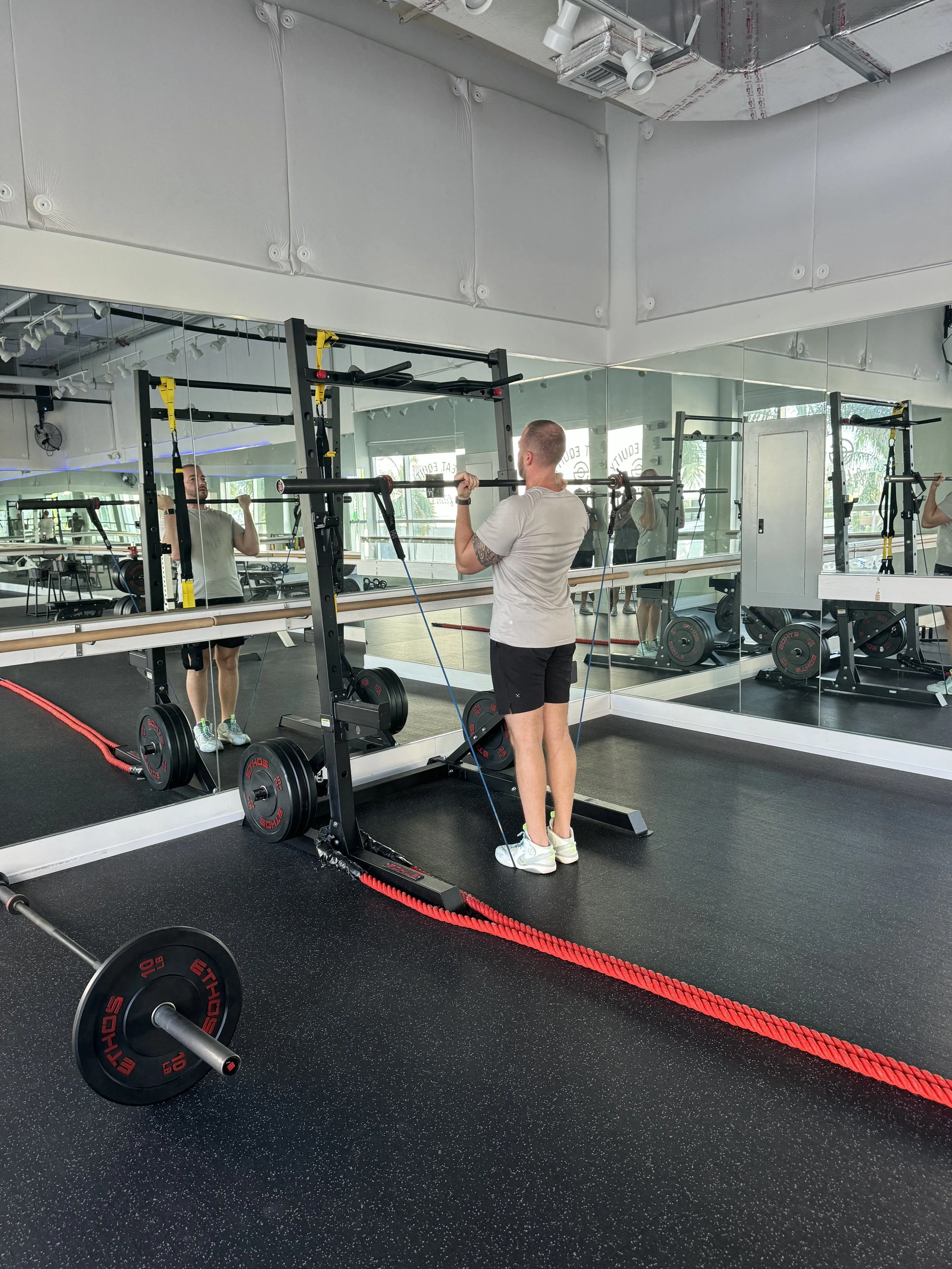 Man doing resistance-band pull-ups on a power rack at Sweat Equity Fitness