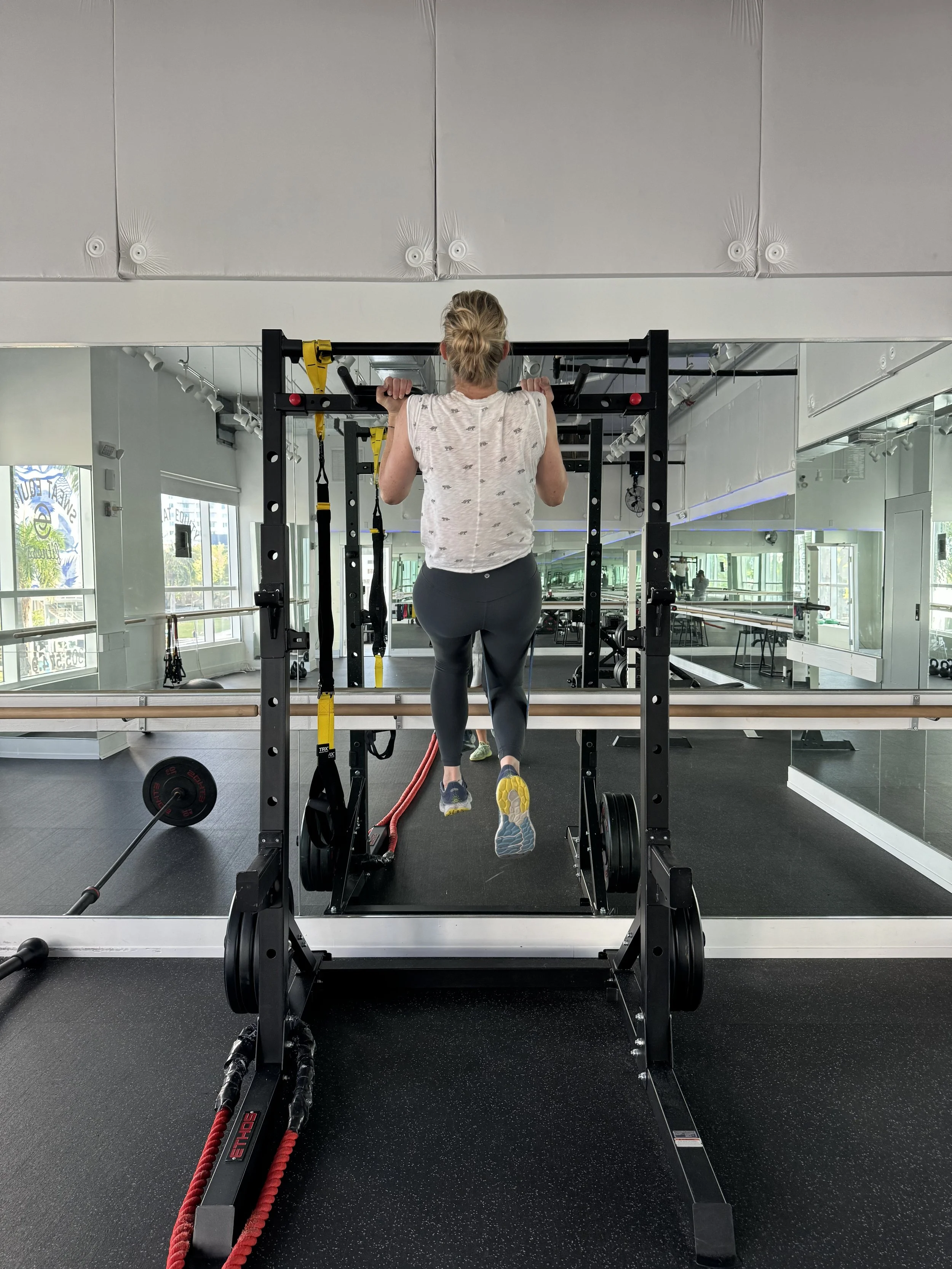 Woman doing pull-ups on a power rack at Sweat Equity Fitness
