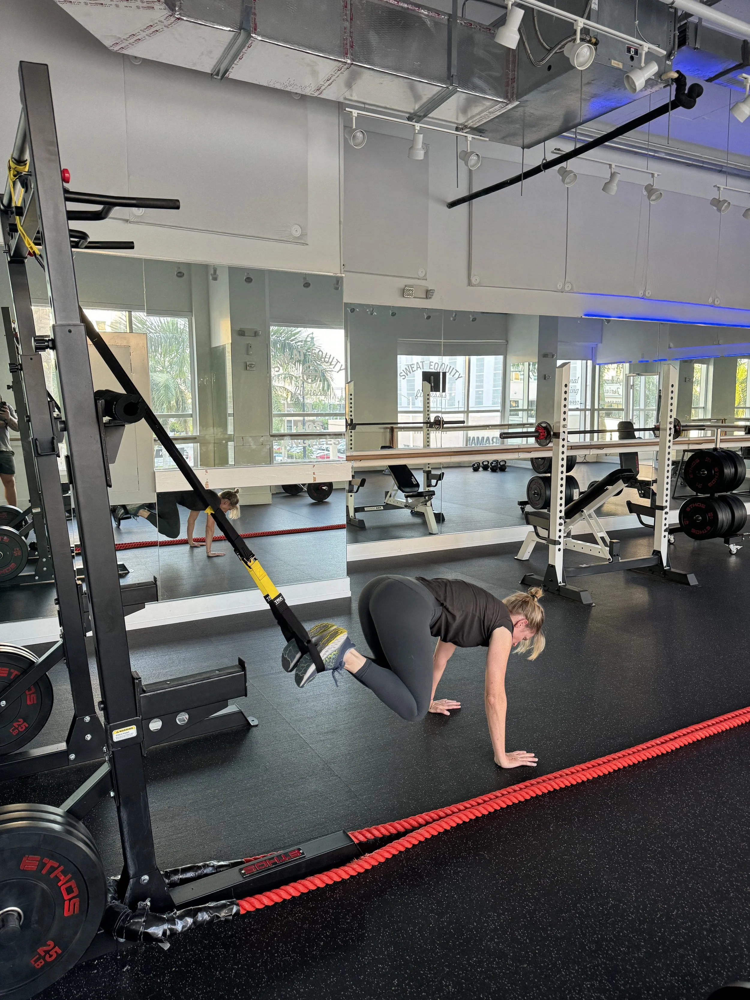 Woman doing a TRX mountain-climber on the gym floor at Sweat Equity Fitness