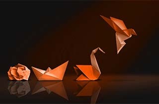 Orange origami sculptures on a dark reflective surface