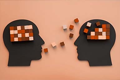Two head silhouettes exchanging puzzle blocks