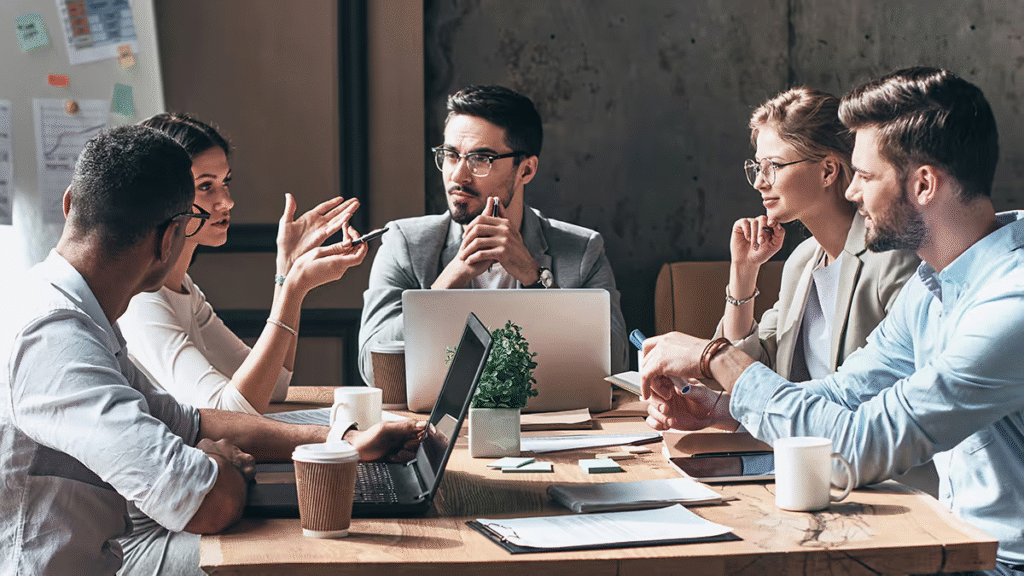 Five professionals in discussion around a conference table