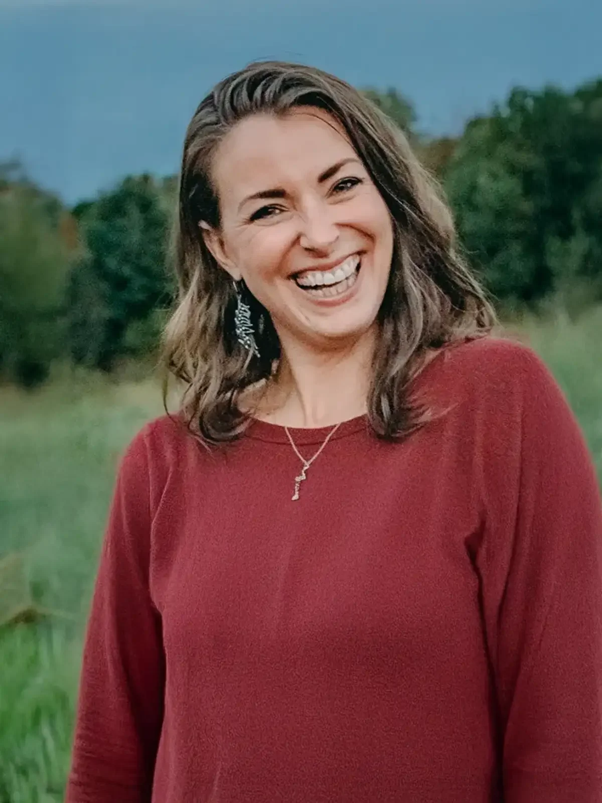 Jessica Wilson, smiling in a red sweater in a field