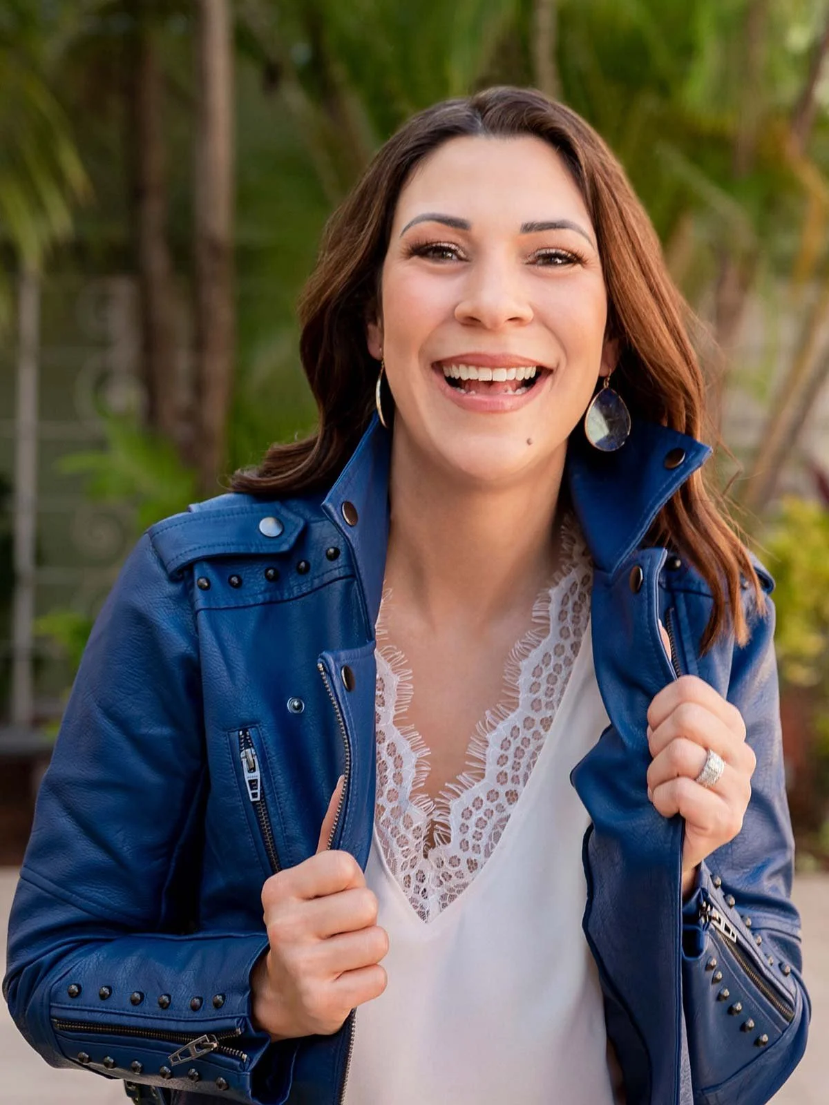 Athena Q., smiling in a blue leather jacket outdoors