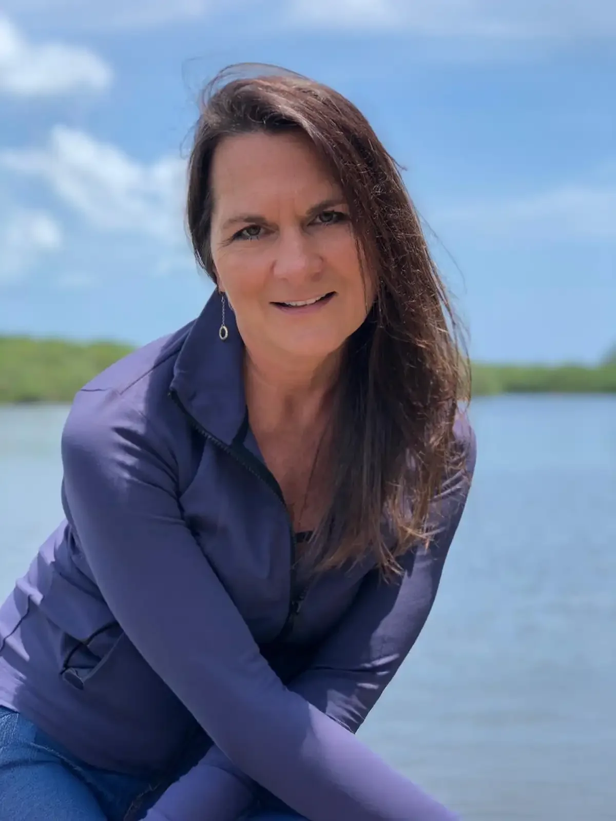 Lydia Clark, smiling in a purple jacket seated by the waterfront