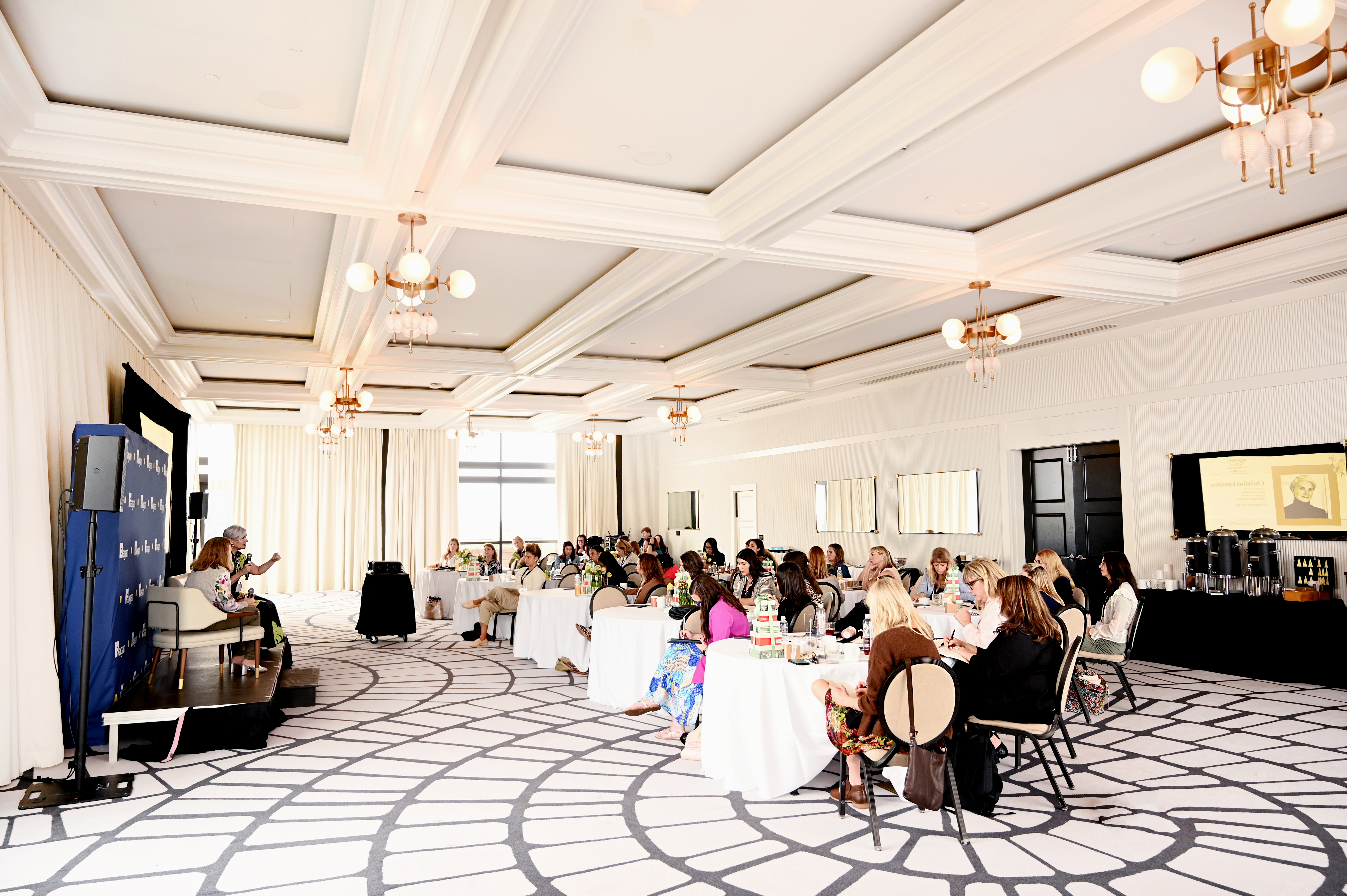 Large ballroom session with professional women seated at round tables