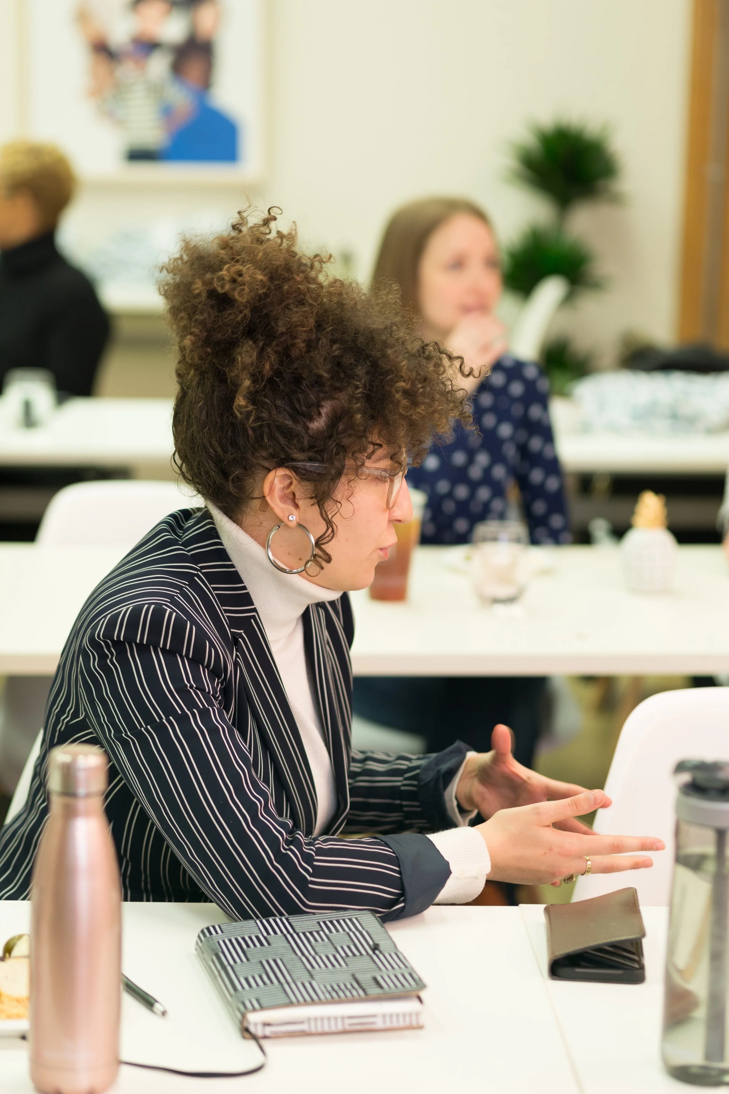 Woman in a striped blazer speaking animatedly at a Lofti workshop table