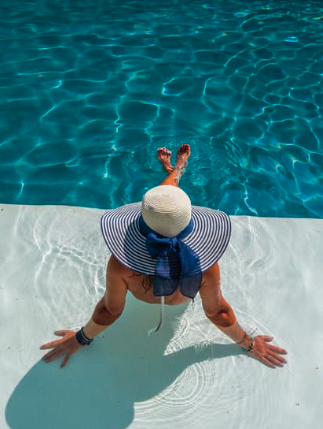Woman in a sun hat resting at the edge of a resort pool