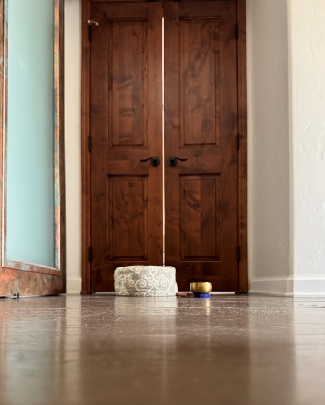 Meditation cushion and singing bowl before rustic wooden doors