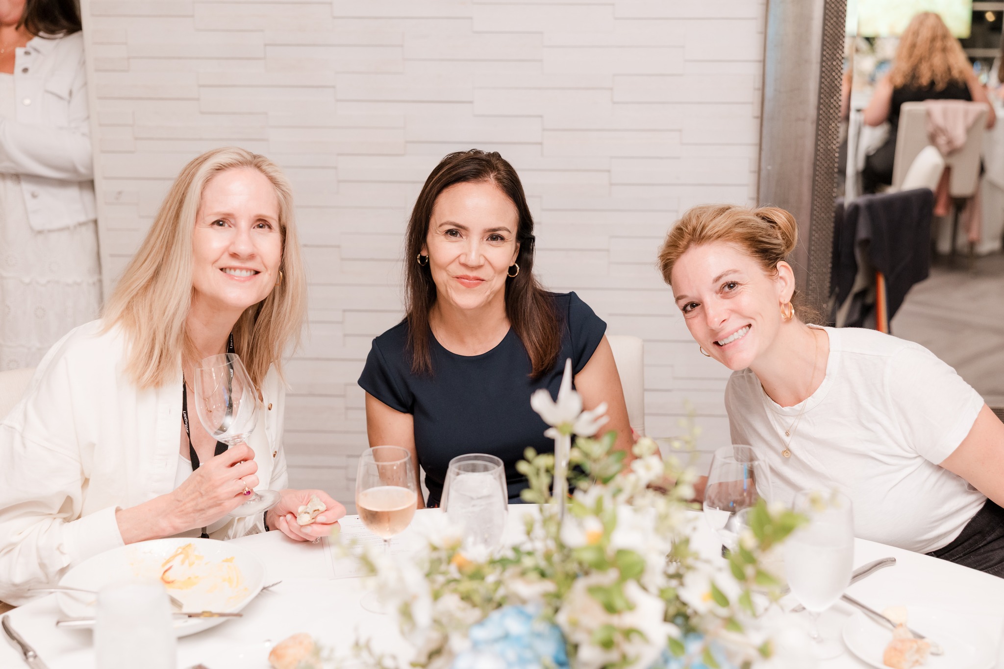 Three professional women at a dinner table during an executive network gathering