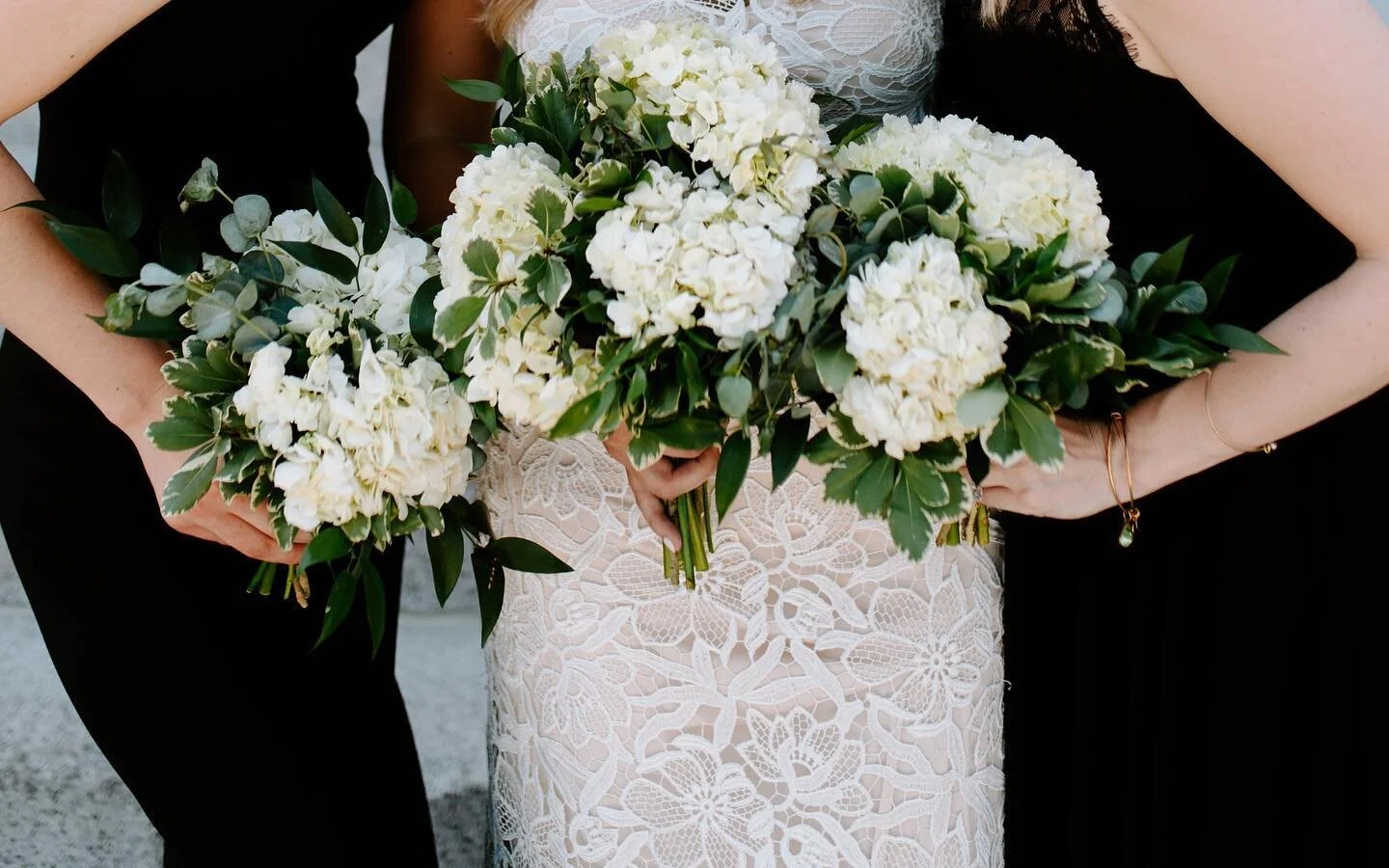 Bride and two bridesmaids holding white hydrangea and greenery bouquets