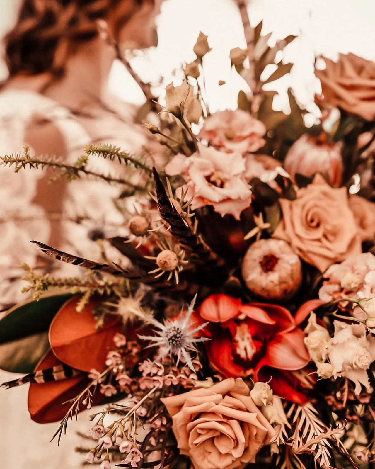 Dramatic boho bridal bouquet with dusty roses, anthurium, feathers, and lisianthus