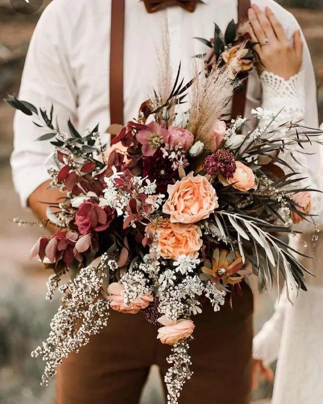 Boho bridal bouquet with pampas grass and garden roses held by a couple