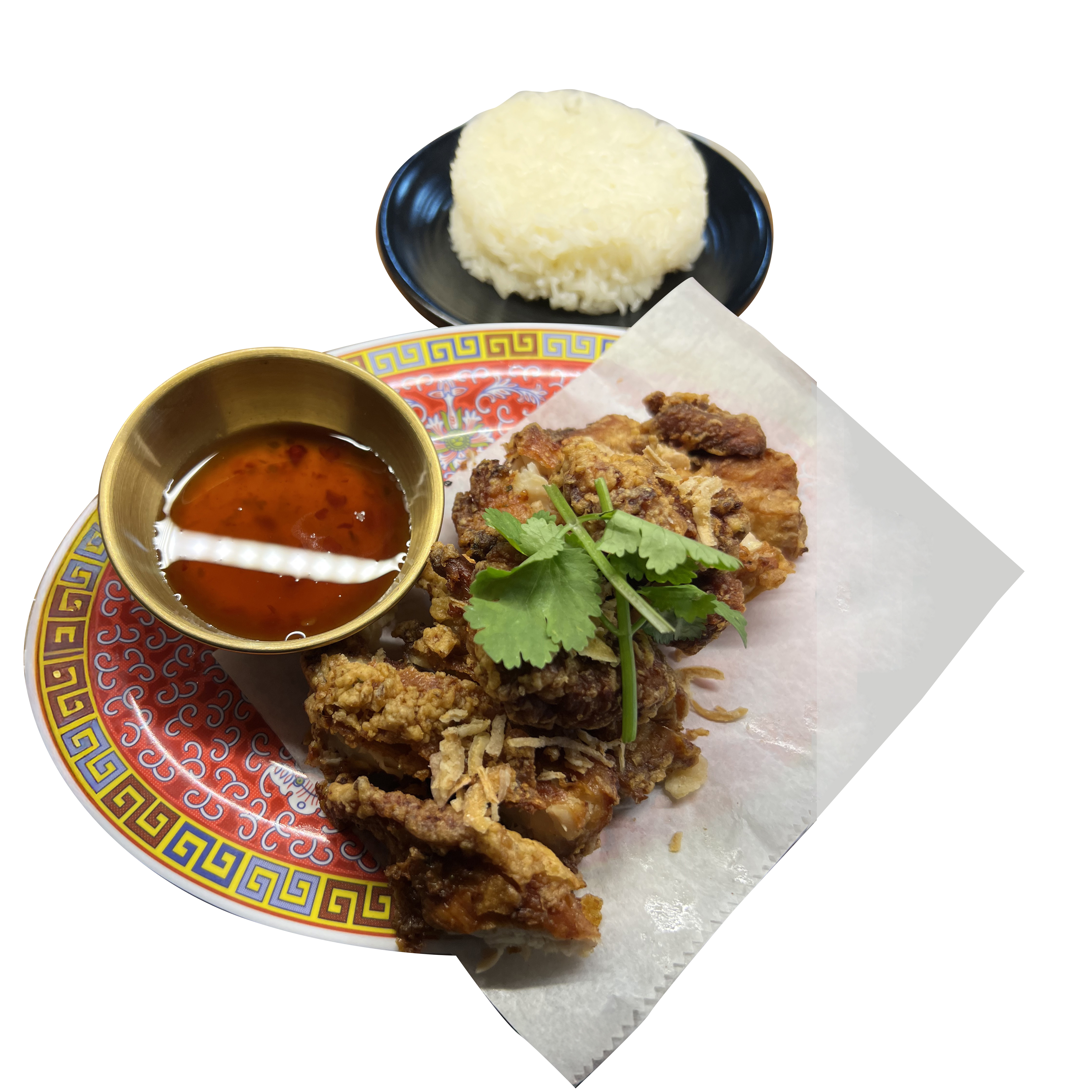 Crispy fried chicken on a decorative red-and-gold Thai plate with dipping sauce and sticky rice
