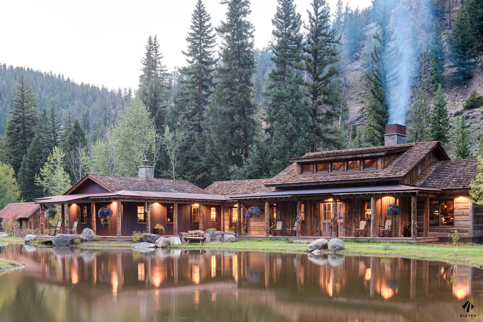 Rustic luxury mountain lodge reflected in a still pond at dusk