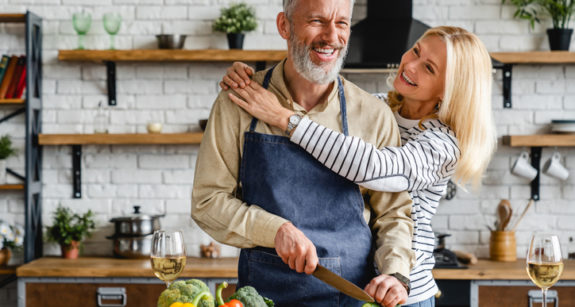 A smiling couple cooking together in their kitchen