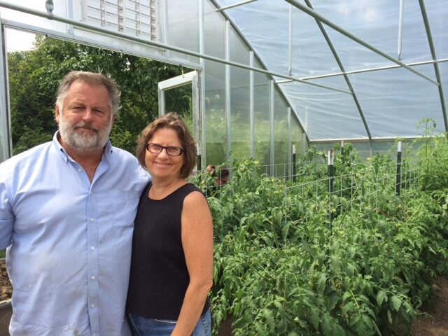 Mary and Ashley standing together inside a greenhouse surrounded by tomato plants