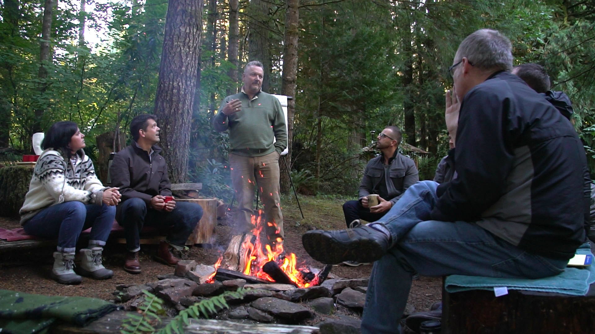 Brad Kleiner sitting by a campfire outdoors at dusk