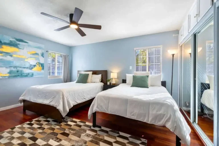 Bedroom with two beds, a ceiling fan, blue walls and hardwood floor