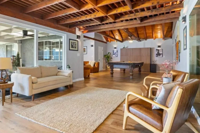 Common area with exposed wood-beam ceiling, sofas and a pool table