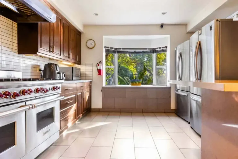 Professional kitchen with stainless steel appliances, dark wood cabinets and a bay window