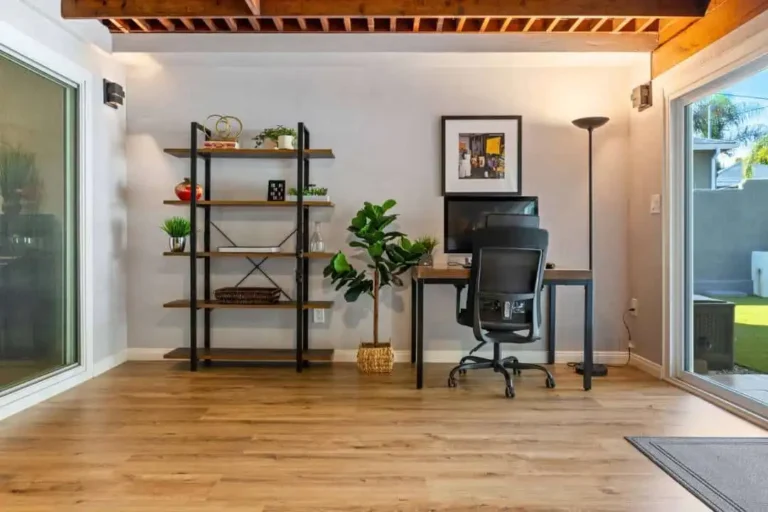 Interior home office and study with shelving, a desk and ergonomic chair under wood-beam ceiling