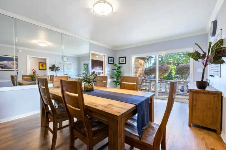 Dining room with a wooden table and chairs, mirror wall and garden view