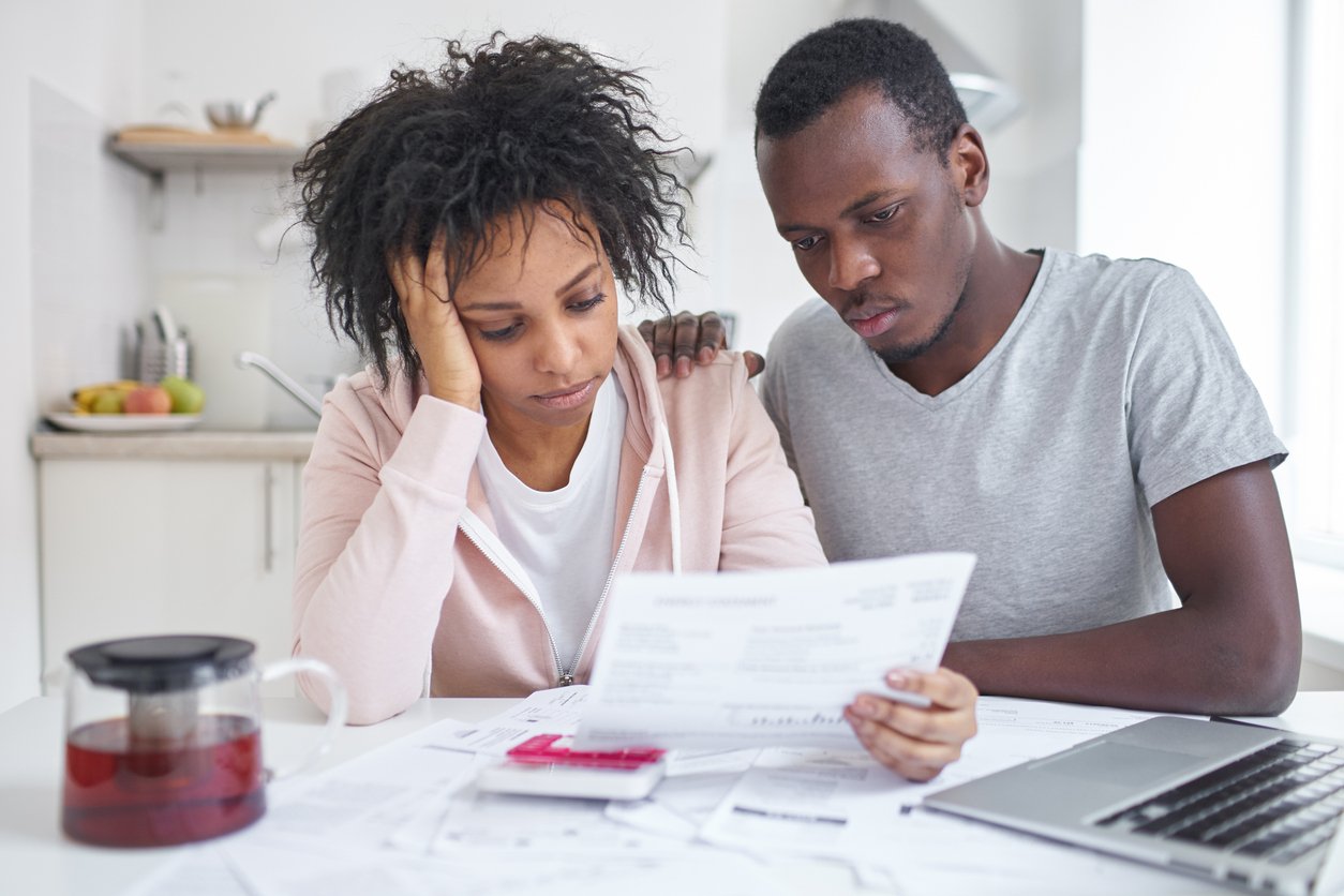 A couple at a kitchen table reviewing bills and paperwork.