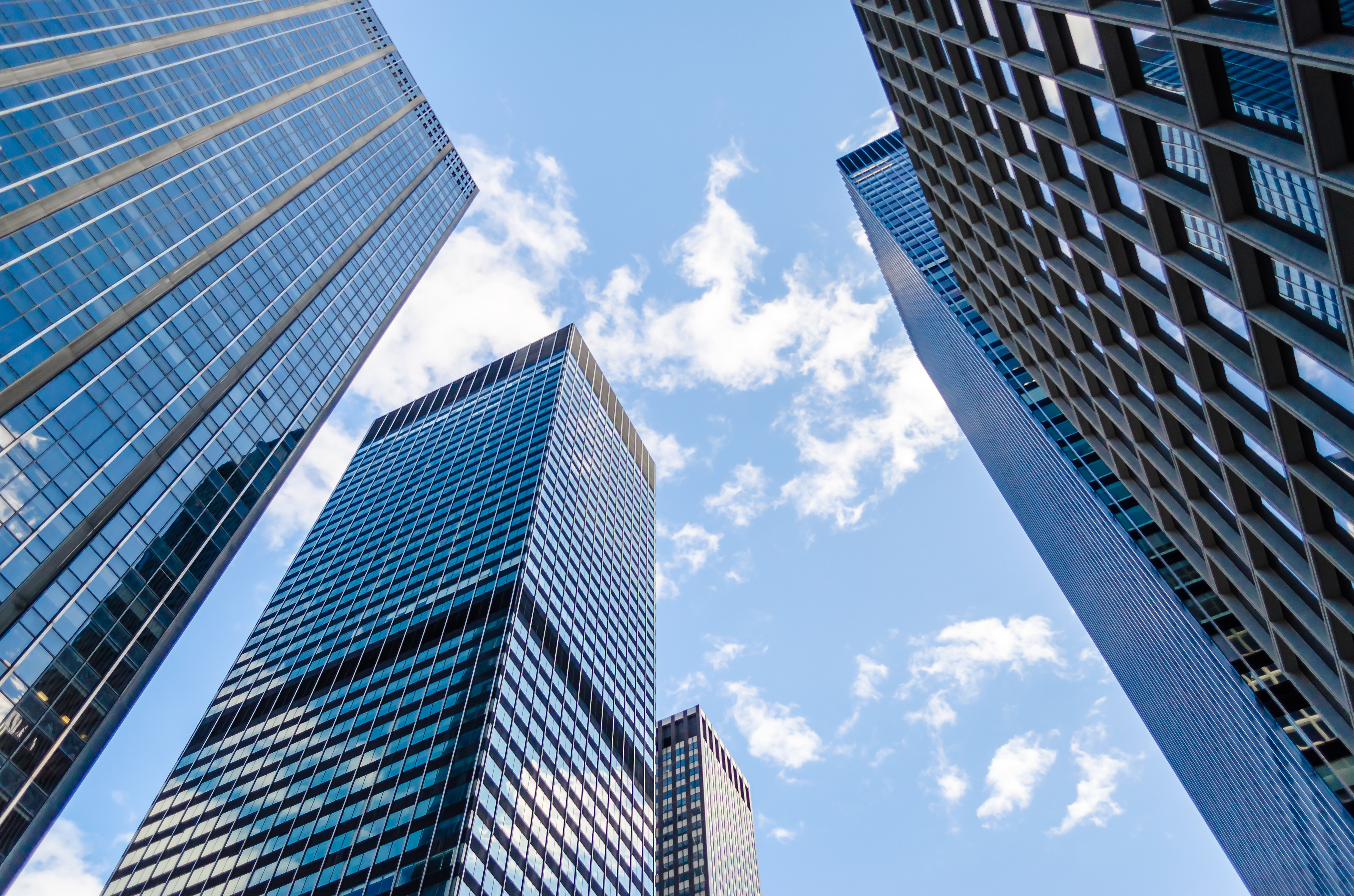 Upward view of glass-and-steel skyscrapers against a blue sky