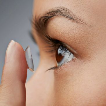 Close-up of a person inserting a contact lens into their eye