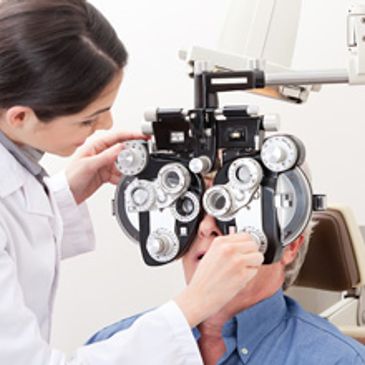 Optometrist performing an eye exam on a patient using a phoropter at HMY Vision