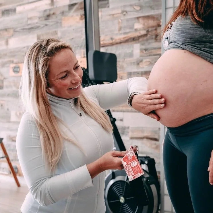 Dr. Heidi Gastler in a white jacket taping a pregnant woman's belly