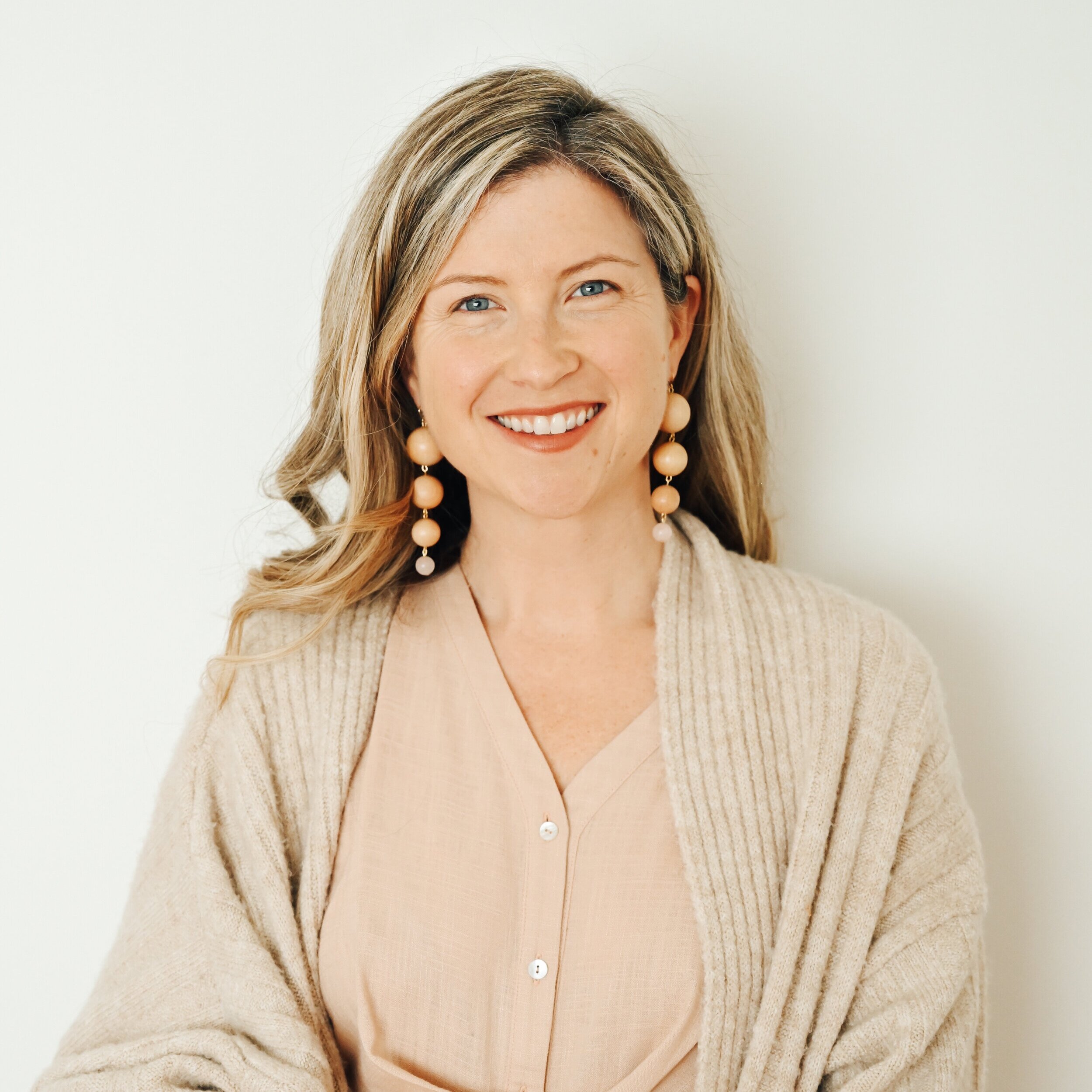 Dr. Jenny Stofer, DC, in a blush cardigan with bead earrings