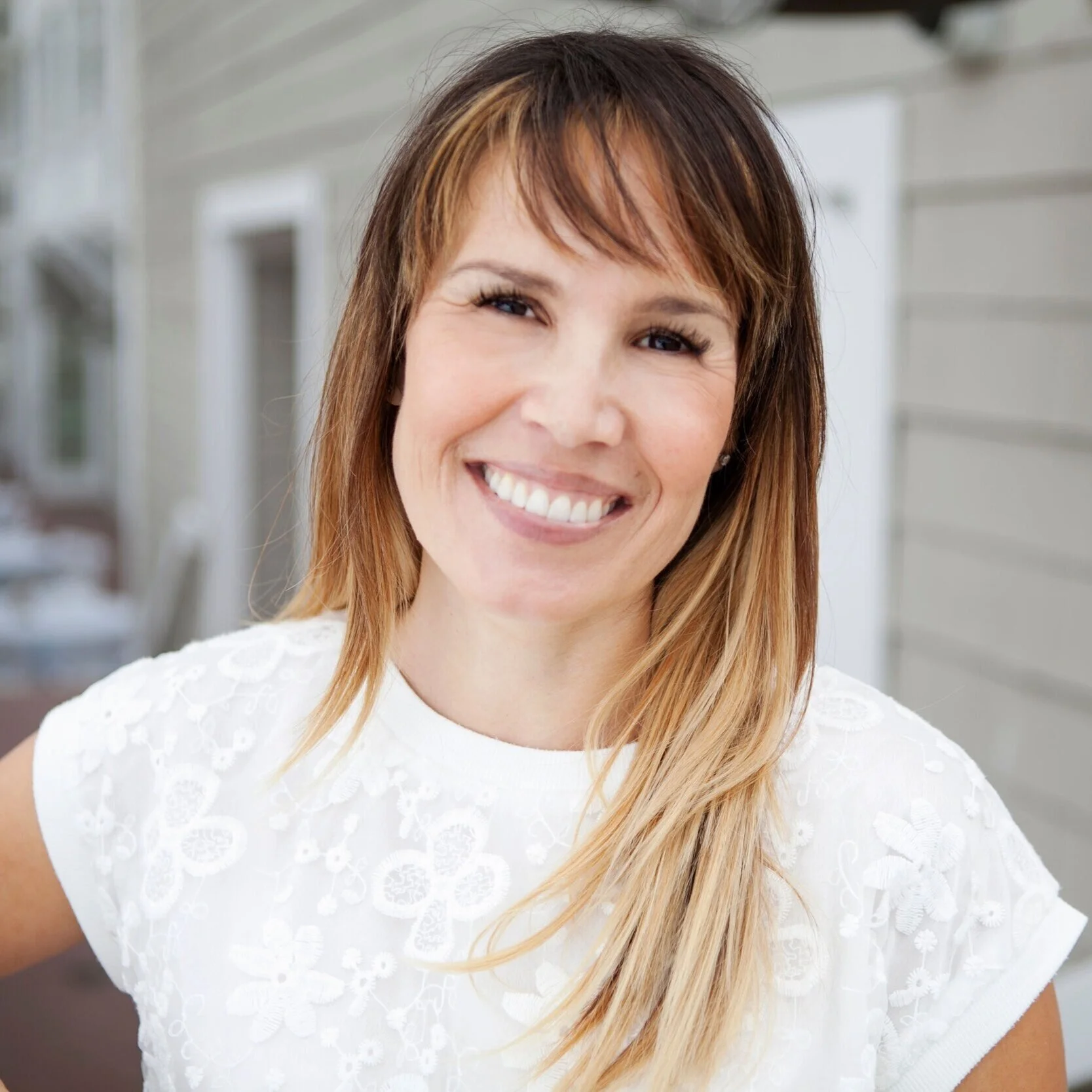Crystal Sol Hays, founder of hōm, smiling in a white embroidered top