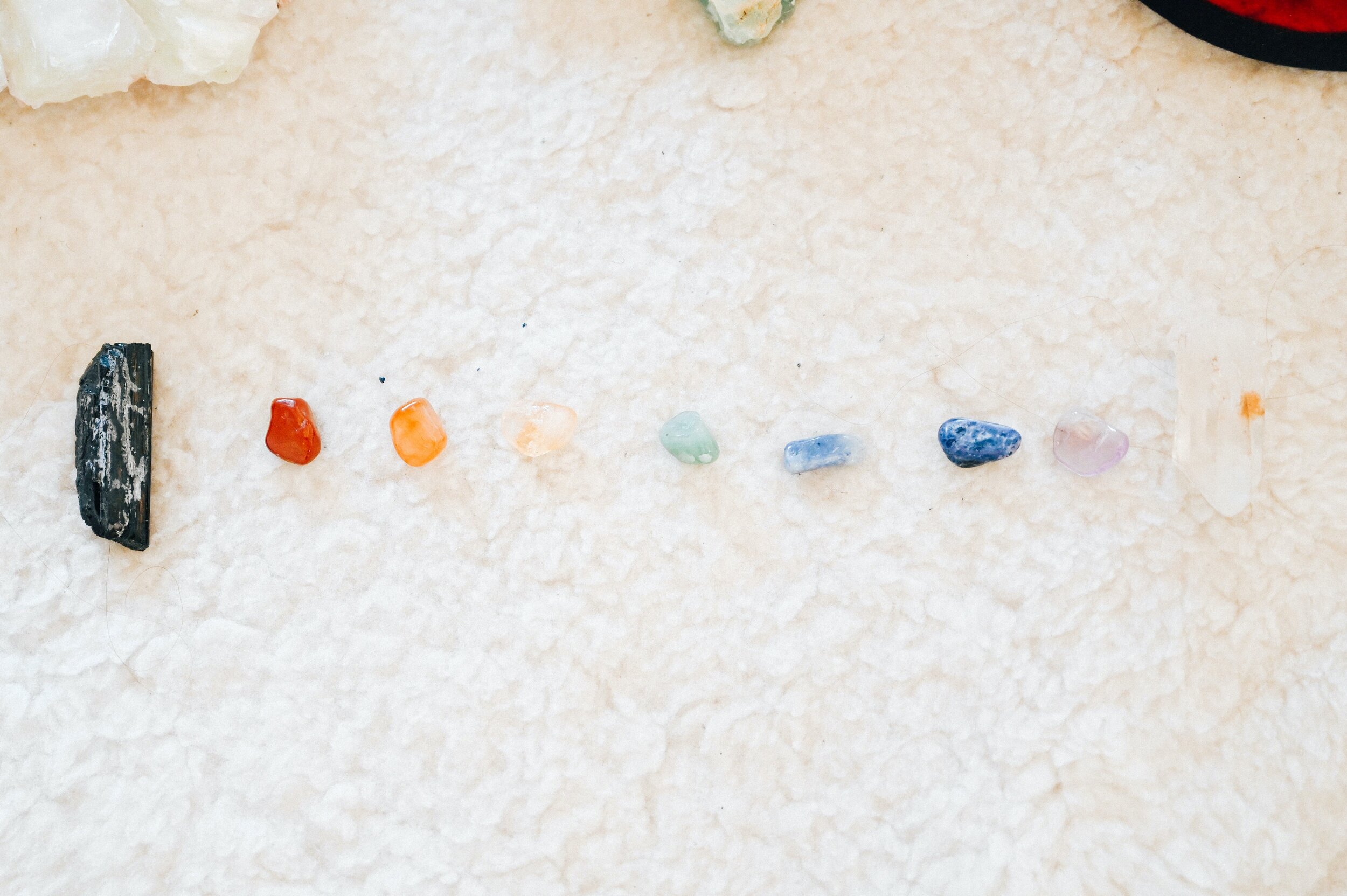 A row of colorful healing crystals arranged on a soft white rug