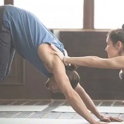 Two people practicing an advanced partner acro-yoga pose in the studio