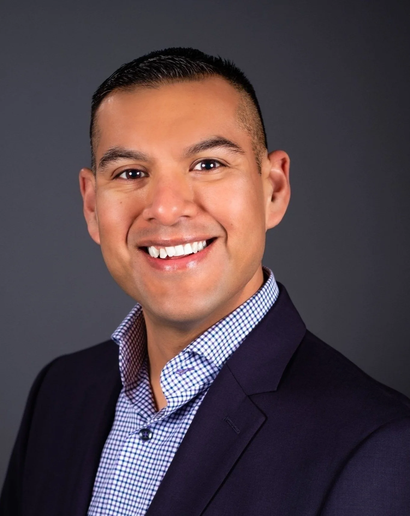 Alberto Segura, Jr., PT, DPT — headshot in a navy blazer and checked shirt