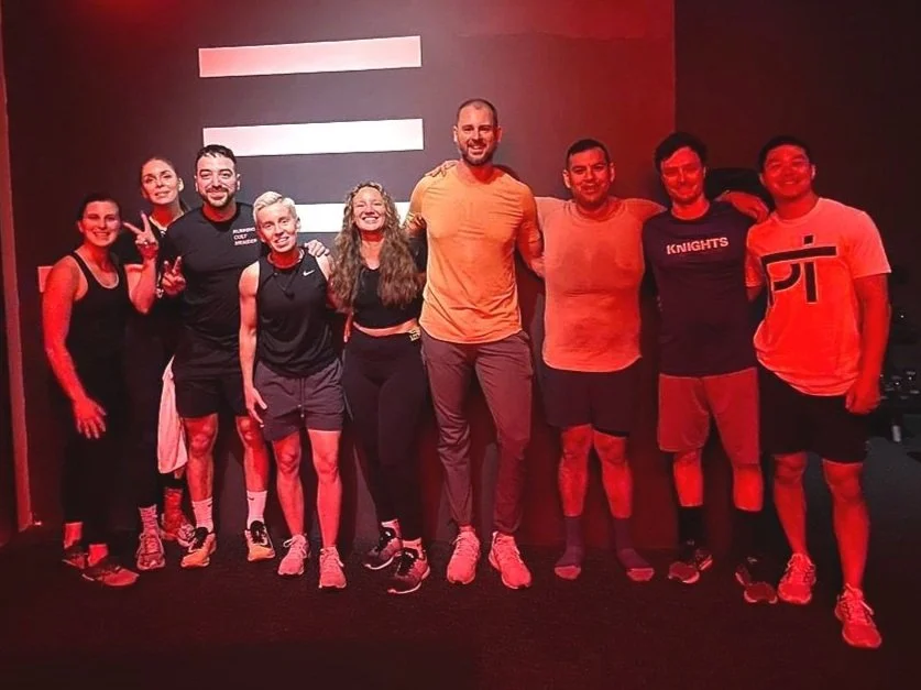 The House of Physical Therapy team posing together in a red-lit gym after a LIFTONIC class