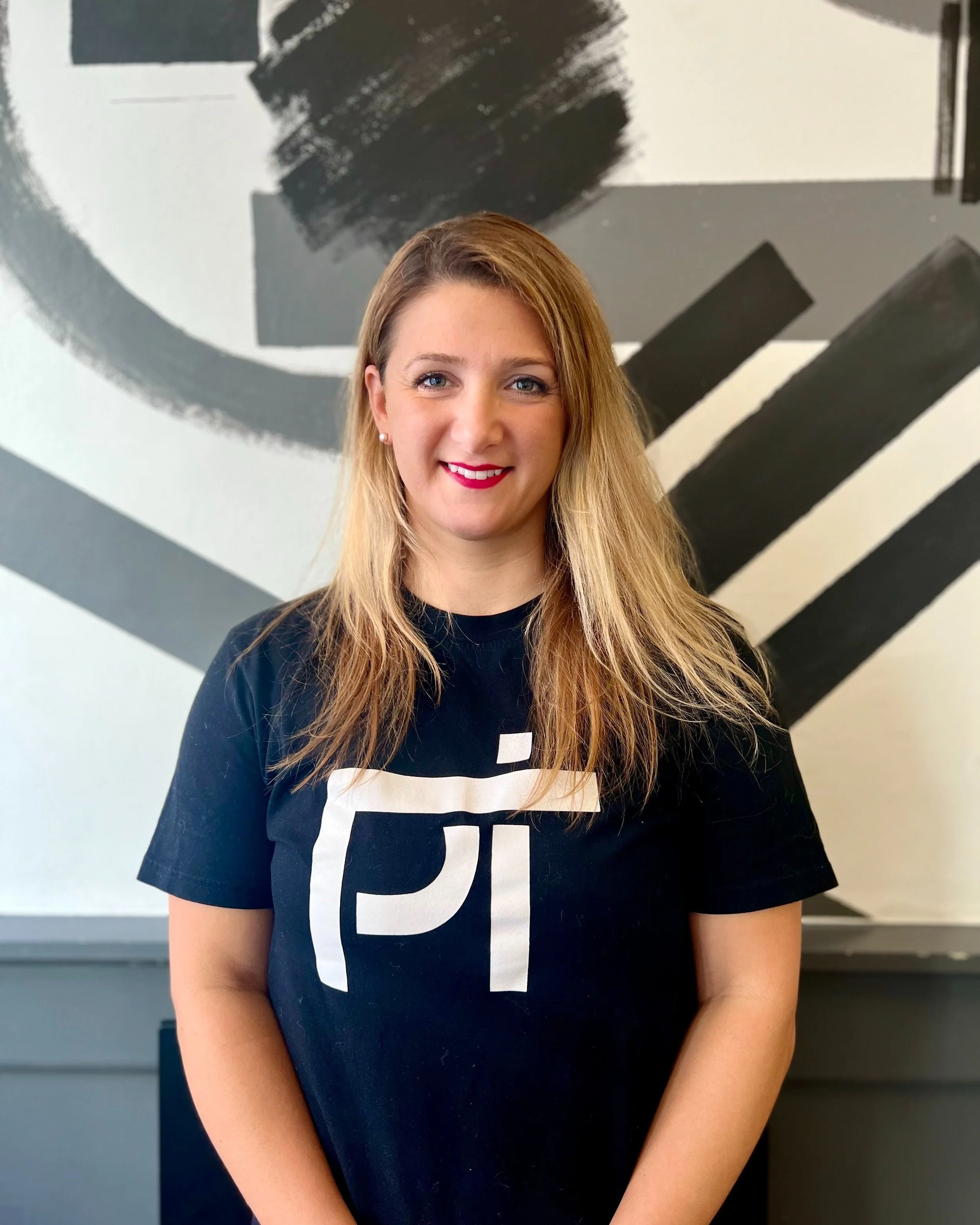 Jillian Proniewych, PT, DPT in a black House of Physical Therapy tee in front of a black-and-white mural