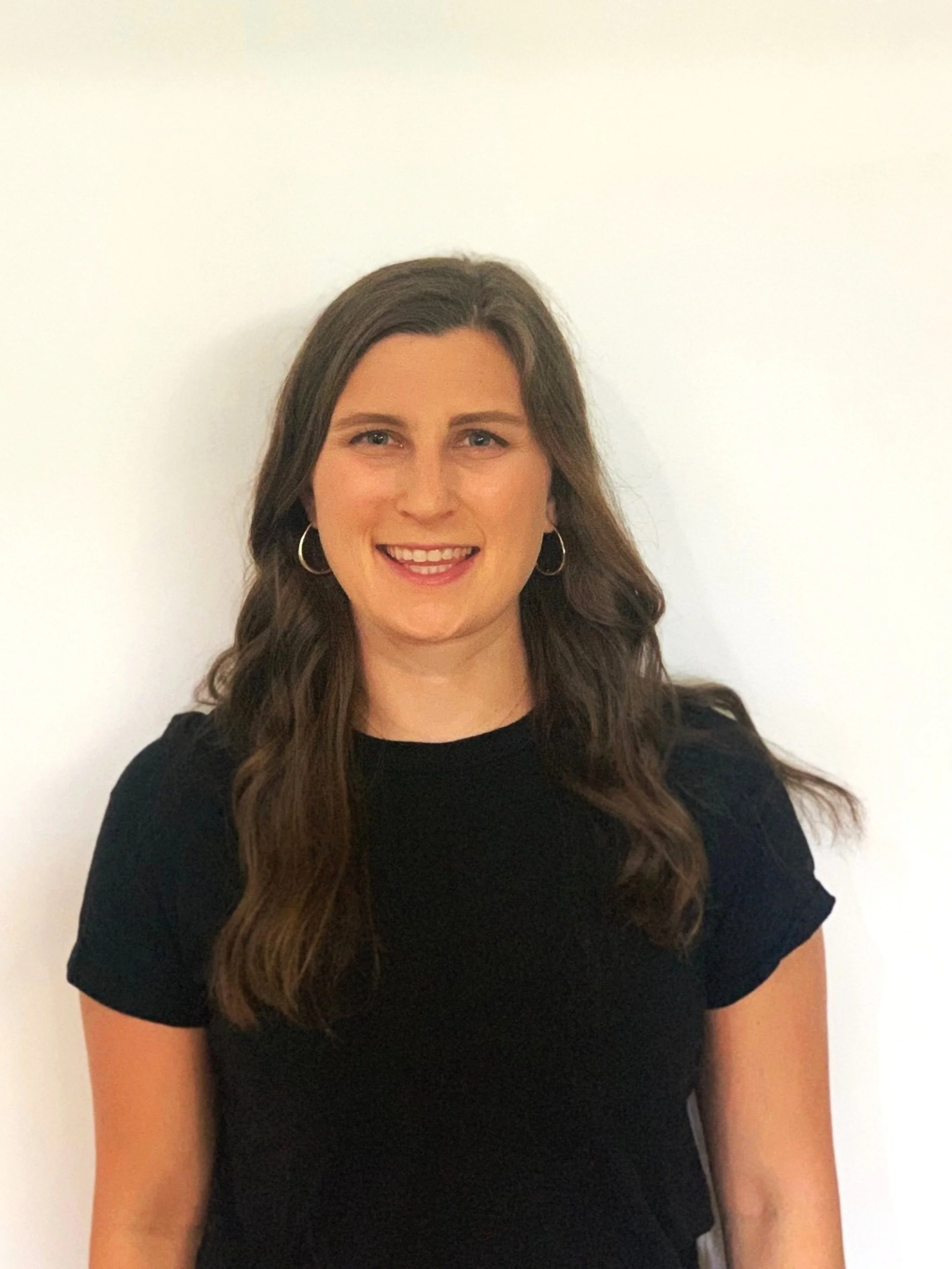 Julia Schindel, PT, DPT — headshot in a black top against a white wall