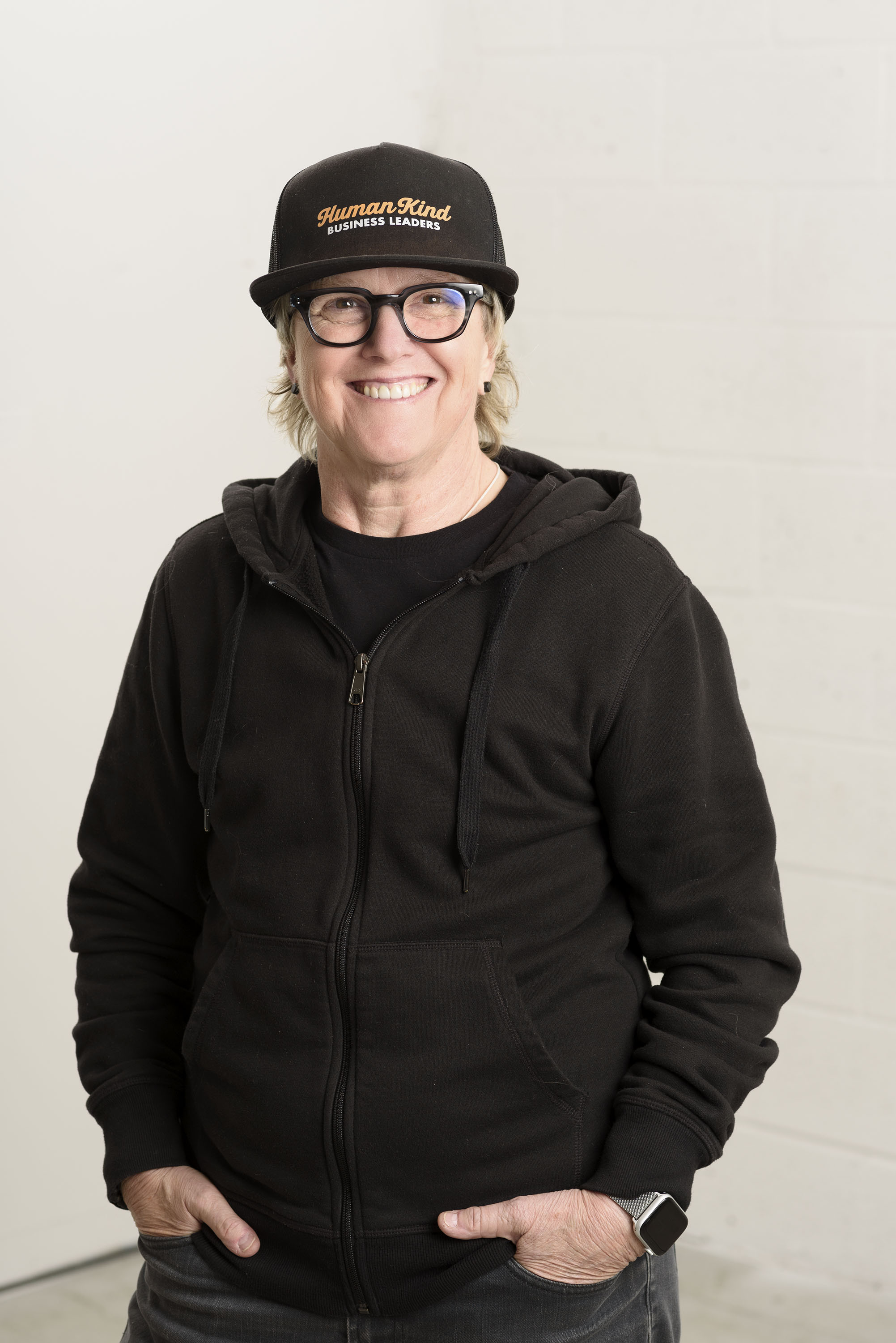 Beck Sydow, founder of HumanKind Business Leaders, smiling in a black HumanKind Business Leaders cap and hoodie