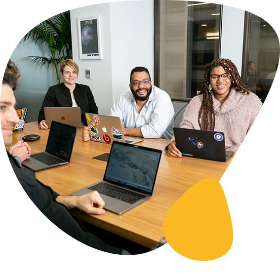 Diverse team of four professionals smiling around a conference table with laptops