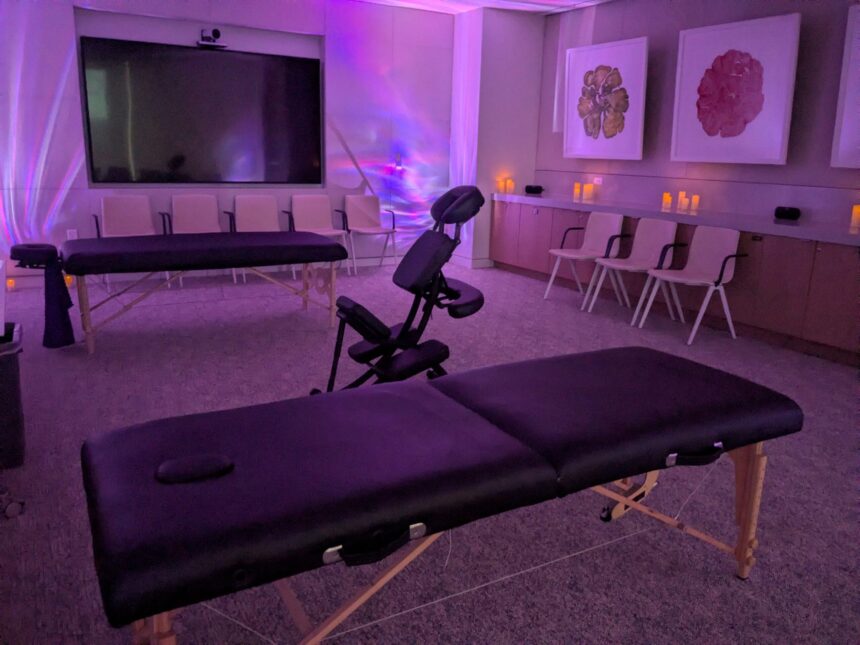 Corporate wellness room with massage tables and chairs under purple ambient lighting