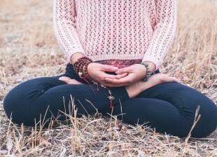 Penpa Dolma seated in meditation in a field, holding mala beads in her lap